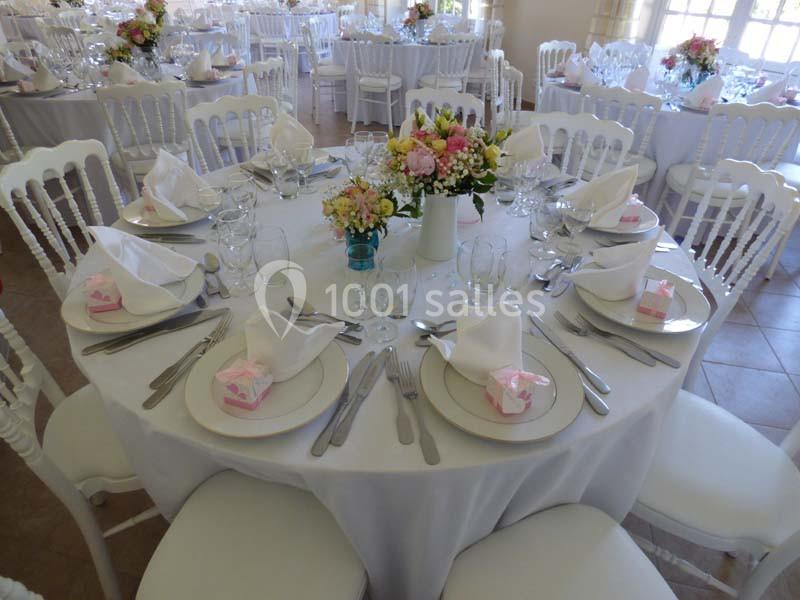 Table ronde décorée pour un événement, avec nappes blanches, vaisselle élégante et centre de table floral.