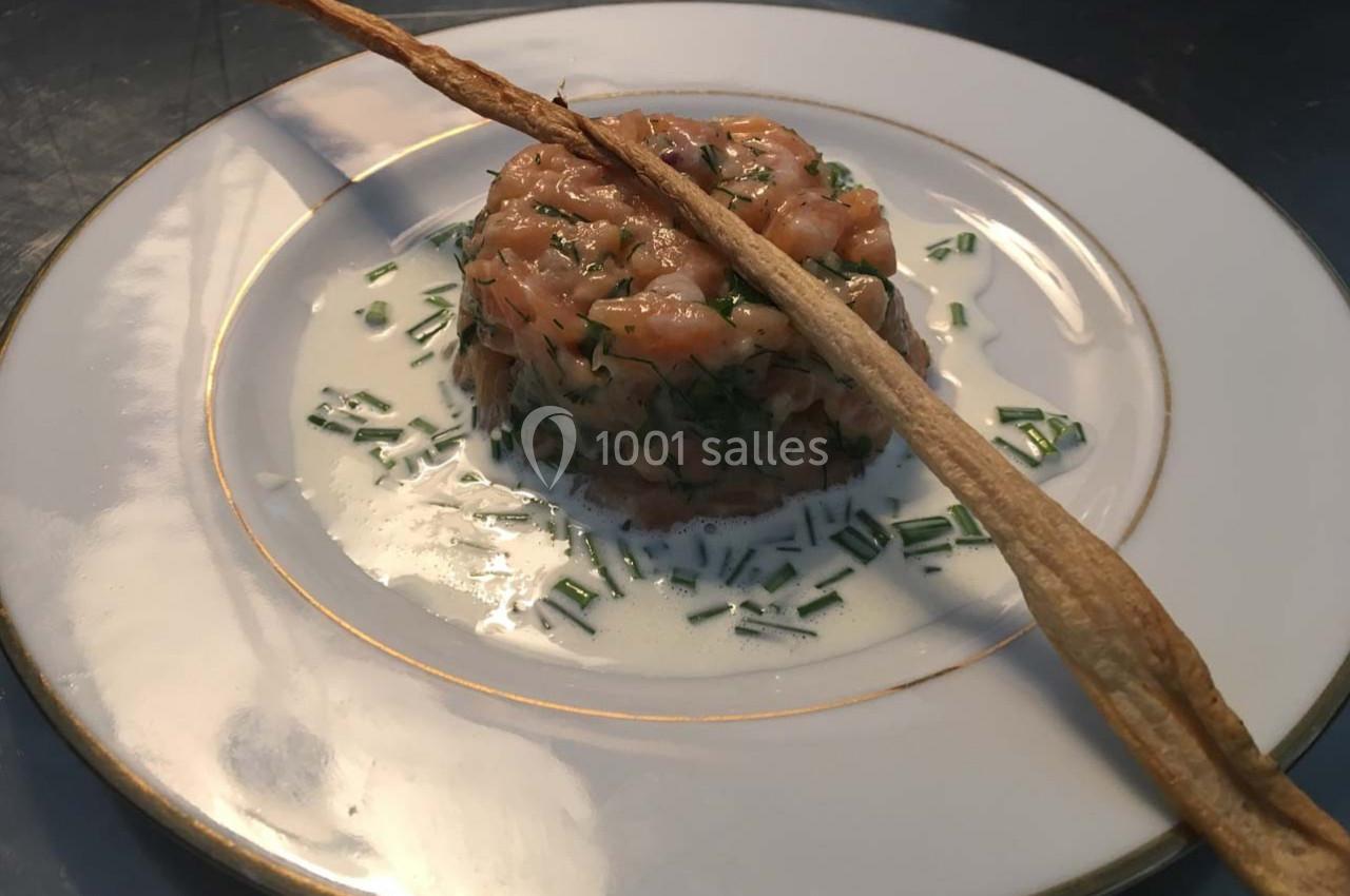 Tartare de saumon servi avec une sauce crémeuse aux herbes et décoré d'une fine tuile croustillante.