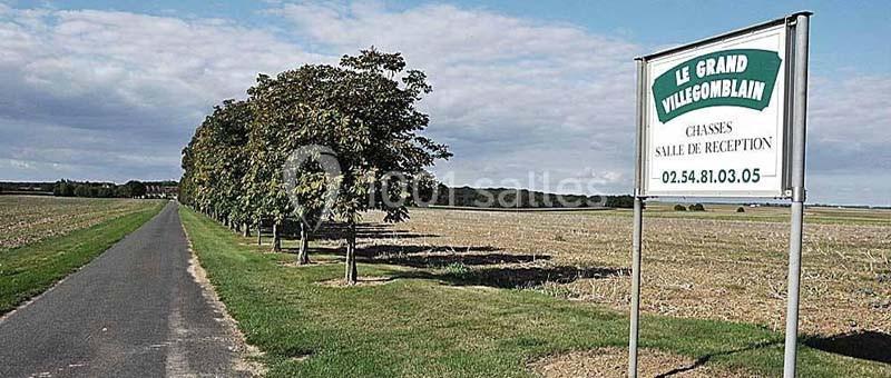 Panneau indiquant ’Le Grand Villeboublain’ près d'une route bordée d'arbres dans un paysage rural.