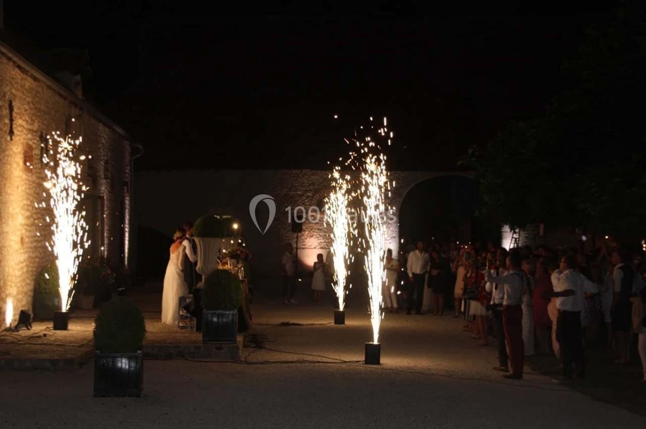 Un couple danse en extérieur de nuit entouré de fontaines d'étincelles, sous le regard des invités.