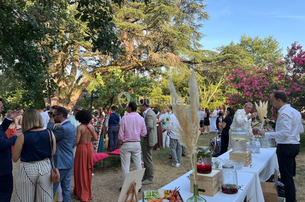 Groupe de personnes socialisant dans un jardin lors d'une réception, avec une table de buffet au premier plan.