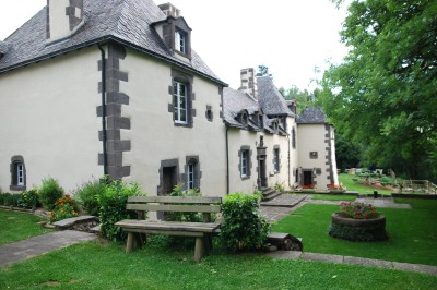 Deux barbecues modernes en métal noir avec plans de travail en bois, installés devant un bâtiment en pierre.