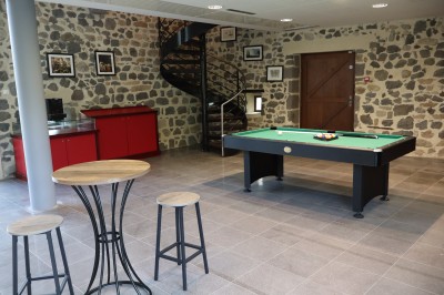 Salle de réunion équipée de chaises rouges et noires, d'un vidéoprojecteur et d'un écran blanc.