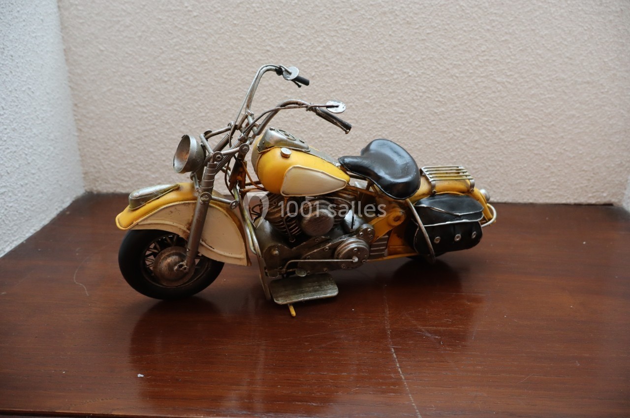 Modèle réduit de moto vintage jaune avec détails métalliques, posé sur une surface en bois.