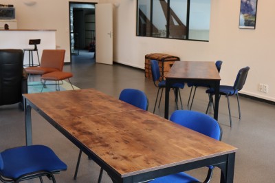 Salle de réunion équipée de chaises rouges et noires, d'un vidéoprojecteur et d'un écran blanc.