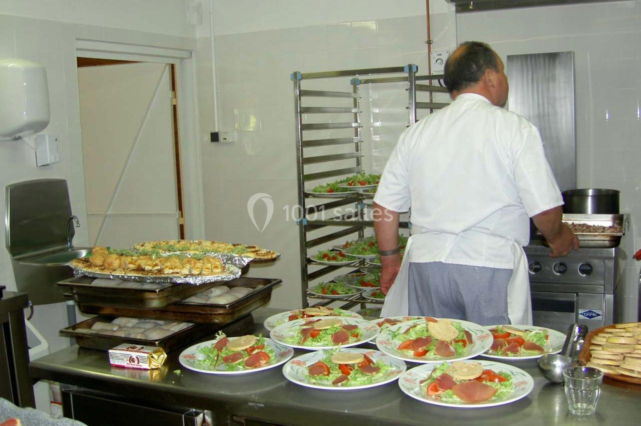 Un cuisinier prépare des plats dans une cuisine professionnelle avec des assiettes de salade prêtes à être servies.