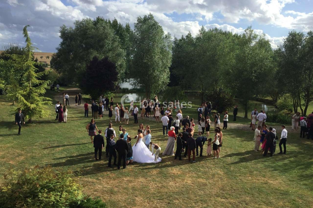 Groupe de personnes rassemblées dans un jardin verdoyant près d'un étang par une journée ensoleillée.