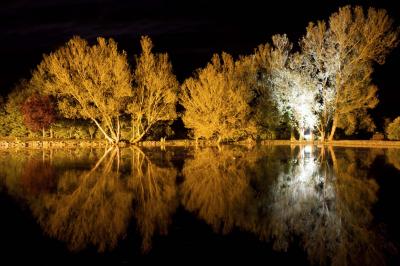 Salle de bain mansardée avec douche en briques de verre, vasques en verre, meubles en bois et fenêtre de toit.