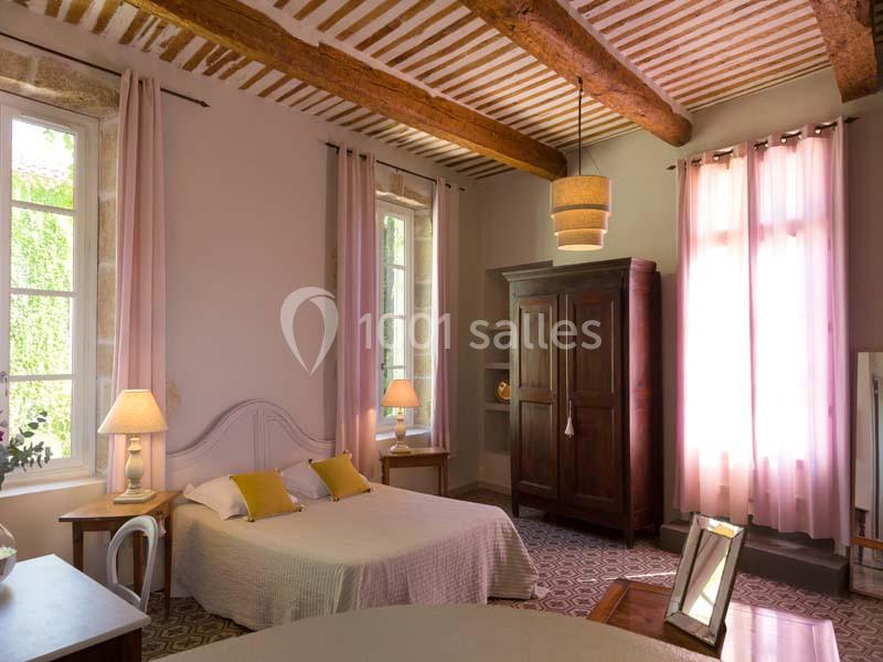 Location salle Pomérols (Hérault) - Domaine Fon de Rey #14 Chambre lumineuse avec lit double, armoire en bois, lampes de chevet et poutres apparentes au plafond.