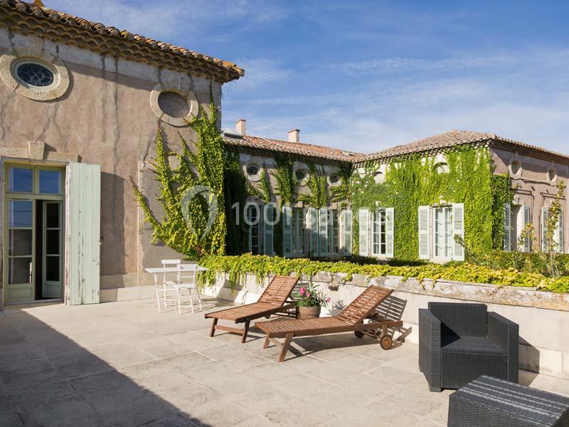 Location salle Pomérols (Hérault) - Domaine Fon de Rey #12 Terrasse ensoleillée avec chaises longues, mobilier d'extérieur et façade recouverte de vigne grimpante.