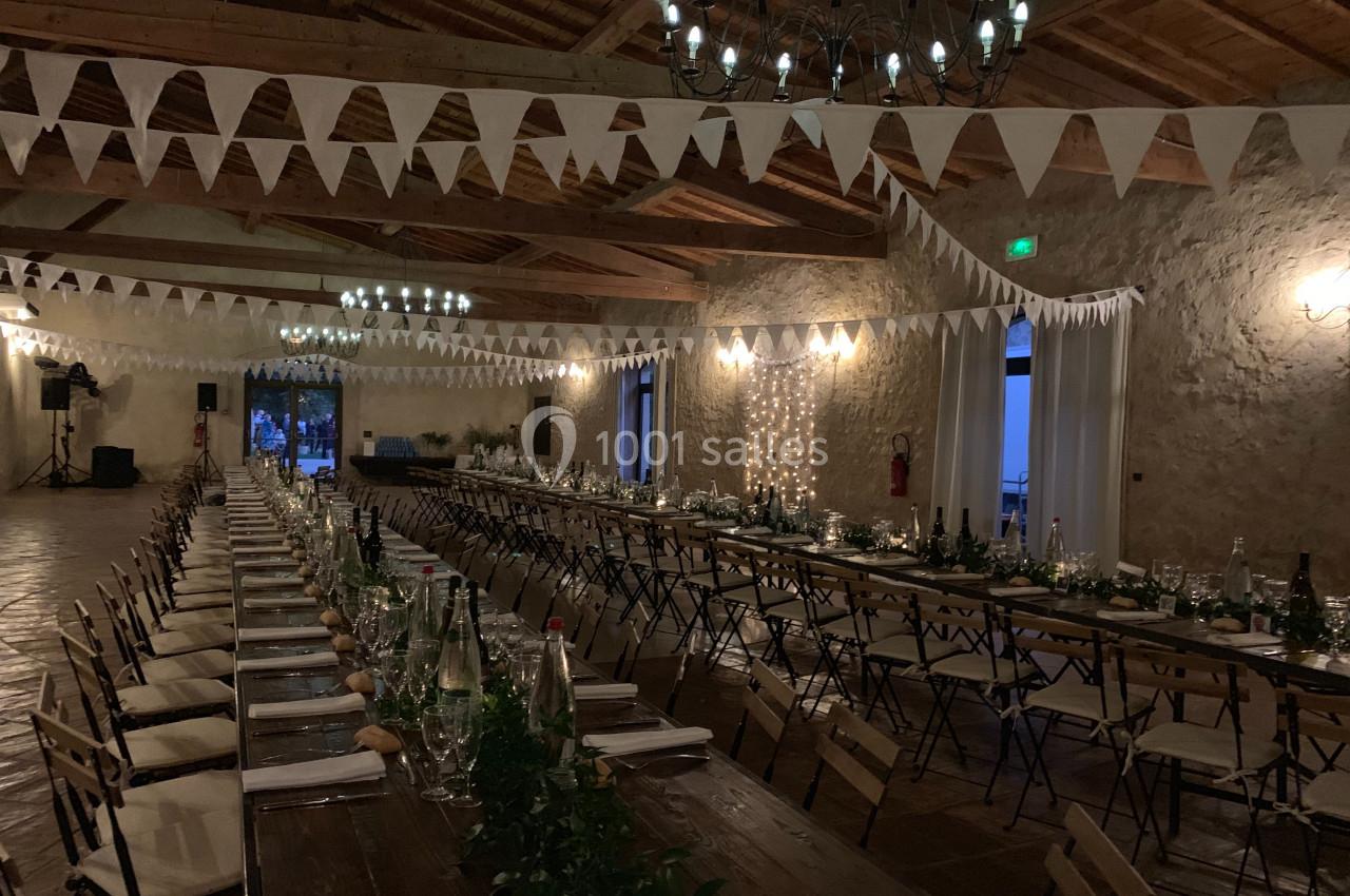 Location salle Pomérols (Hérault) - Domaine Fon de Rey #22 Grande salle décorée pour un événement, avec longues tables en bois, guirlandes lumineuses et fanions suspendus.