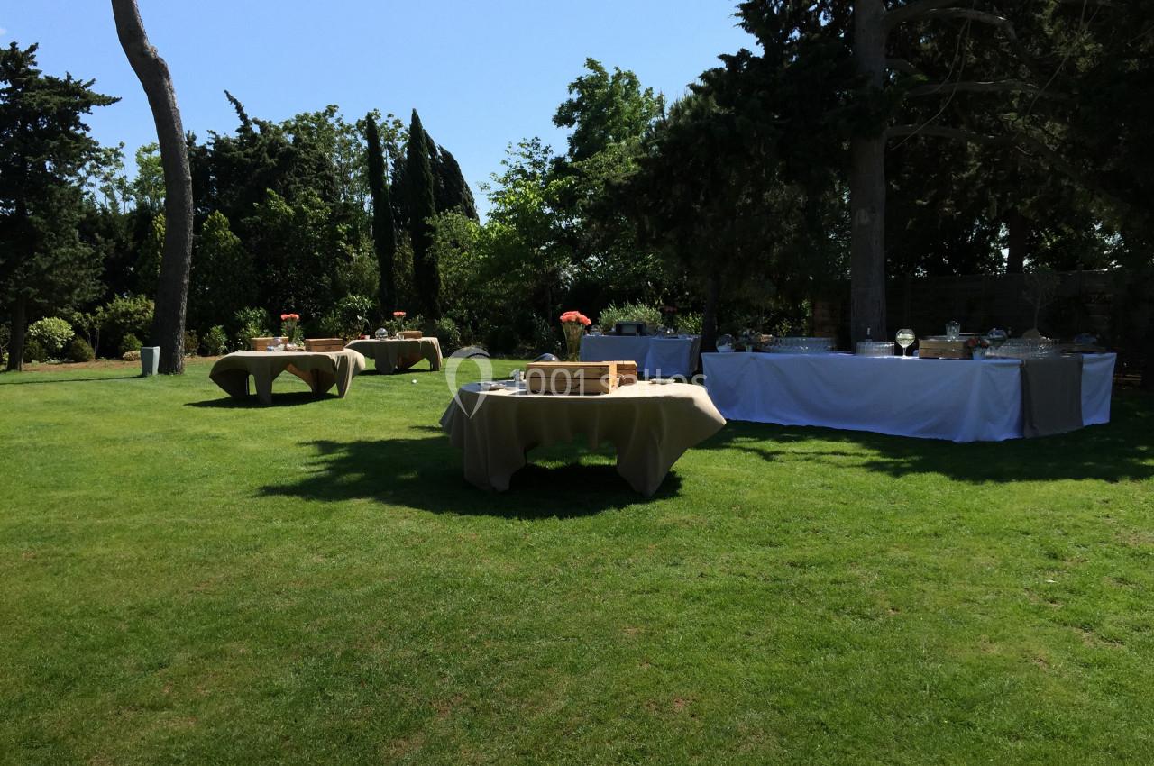 Location salle Pomérols (Hérault) - Domaine Fon de Rey #47 Tables dressées pour un événement en plein air sur une pelouse entourée d'arbres et de verdure.
