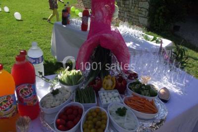 Buffet avec verrines, brochettes et boissons disposés sur une table bleue dans un espace sous tente.