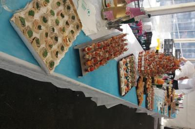 Buffet avec verrines, brochettes et boissons disposés sur une table bleue dans un espace sous tente.