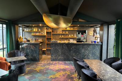 Intérieur d'un bar élégant avec comptoir en marbre sombre, étagères de bouteilles et fauteuils confortables.