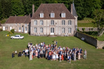 Salon rustique avec murs en pierre, canapés en cuir, table basse et porte ouverte donnant sur un jardin ensoleillé.