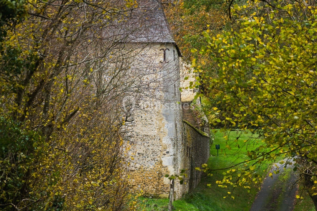 Mur en pierre d'un bâtiment ancien entouré d'arbres et de verdure en automne.