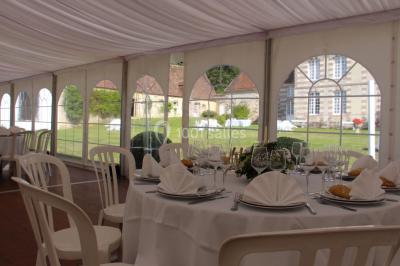 Salon rustique avec murs en pierre, canapés en cuir, table basse et porte ouverte donnant sur un jardin ensoleillé.