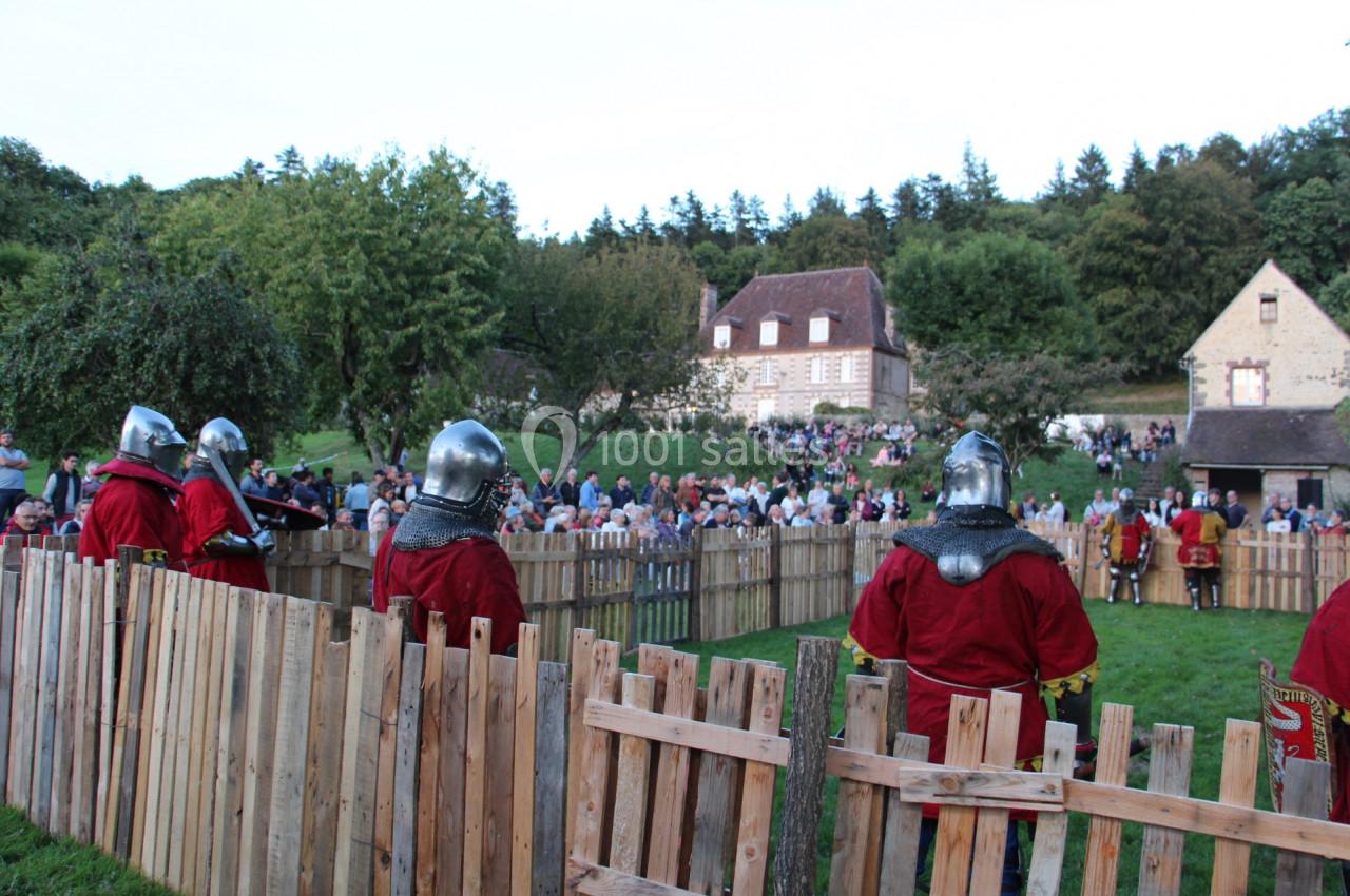 Des chevaliers en armure participent à une reconstitution médiévale devant un public rassemblé en plein air.