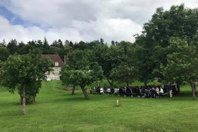 Salon rustique avec murs en pierre, canapés en cuir, table basse et porte ouverte donnant sur un jardin ensoleillé.