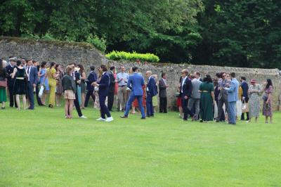 Salon rustique avec murs en pierre, canapés en cuir, table basse et porte ouverte donnant sur un jardin ensoleillé.