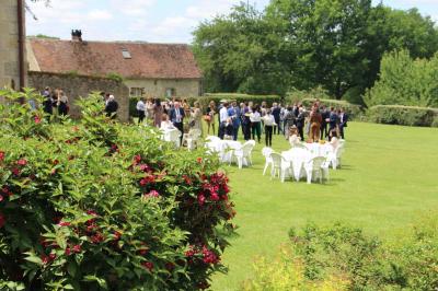 Salon rustique avec murs en pierre, canapés en cuir, table basse et porte ouverte donnant sur un jardin ensoleillé.