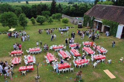 Salon rustique avec murs en pierre, canapés en cuir, table basse et porte ouverte donnant sur un jardin ensoleillé.