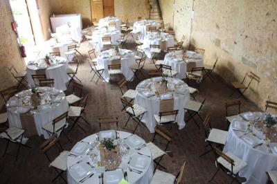 Salon rustique avec murs en pierre, canapés en cuir, table basse et porte ouverte donnant sur un jardin ensoleillé.