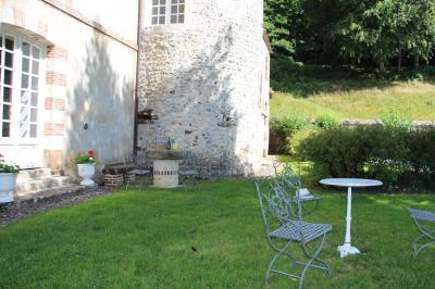Salon rustique avec murs en pierre, canapés en cuir, table basse et porte ouverte donnant sur un jardin ensoleillé.