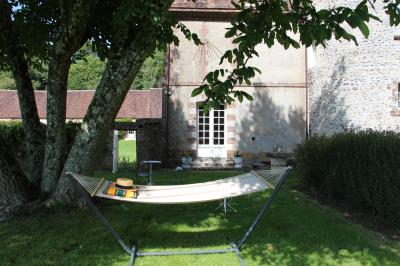Salon rustique avec murs en pierre, canapés en cuir, table basse et porte ouverte donnant sur un jardin ensoleillé.