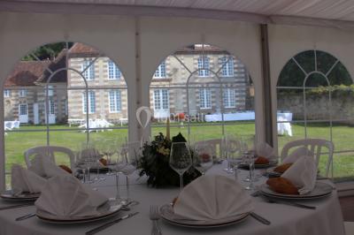 Salon rustique avec murs en pierre, canapés en cuir, table basse et porte ouverte donnant sur un jardin ensoleillé.