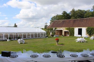 Salon rustique avec murs en pierre, canapés en cuir, table basse et porte ouverte donnant sur un jardin ensoleillé.