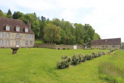 Salon rustique avec murs en pierre, canapés en cuir, table basse et porte ouverte donnant sur un jardin ensoleillé.