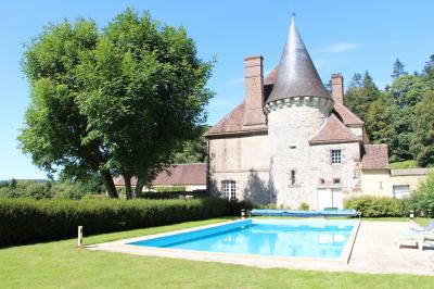 Salon rustique avec murs en pierre, canapés en cuir, table basse et porte ouverte donnant sur un jardin ensoleillé.