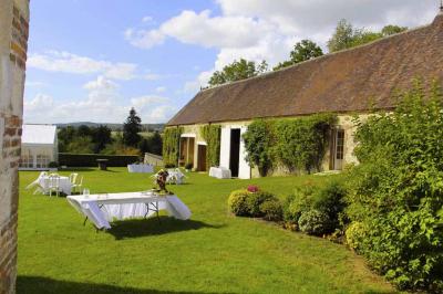 Salon rustique avec murs en pierre, canapés en cuir, table basse et porte ouverte donnant sur un jardin ensoleillé.