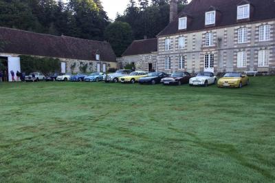 Salon rustique avec murs en pierre, canapés en cuir, table basse et porte ouverte donnant sur un jardin ensoleillé.