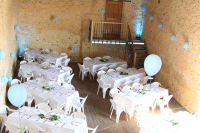 Salon rustique avec murs en pierre, canapés en cuir, table basse et porte ouverte donnant sur un jardin ensoleillé.