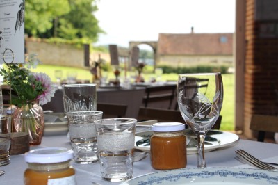 Salon rustique avec murs en pierre, canapés en cuir, table basse et porte ouverte donnant sur un jardin ensoleillé.