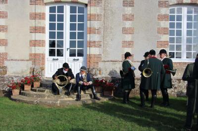 Salon rustique avec murs en pierre, canapés en cuir, table basse et porte ouverte donnant sur un jardin ensoleillé.