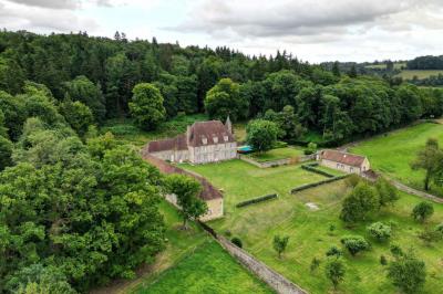 Salon rustique avec murs en pierre, canapés en cuir, table basse et porte ouverte donnant sur un jardin ensoleillé.