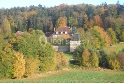 Salon rustique avec murs en pierre, canapés en cuir, table basse et porte ouverte donnant sur un jardin ensoleillé.