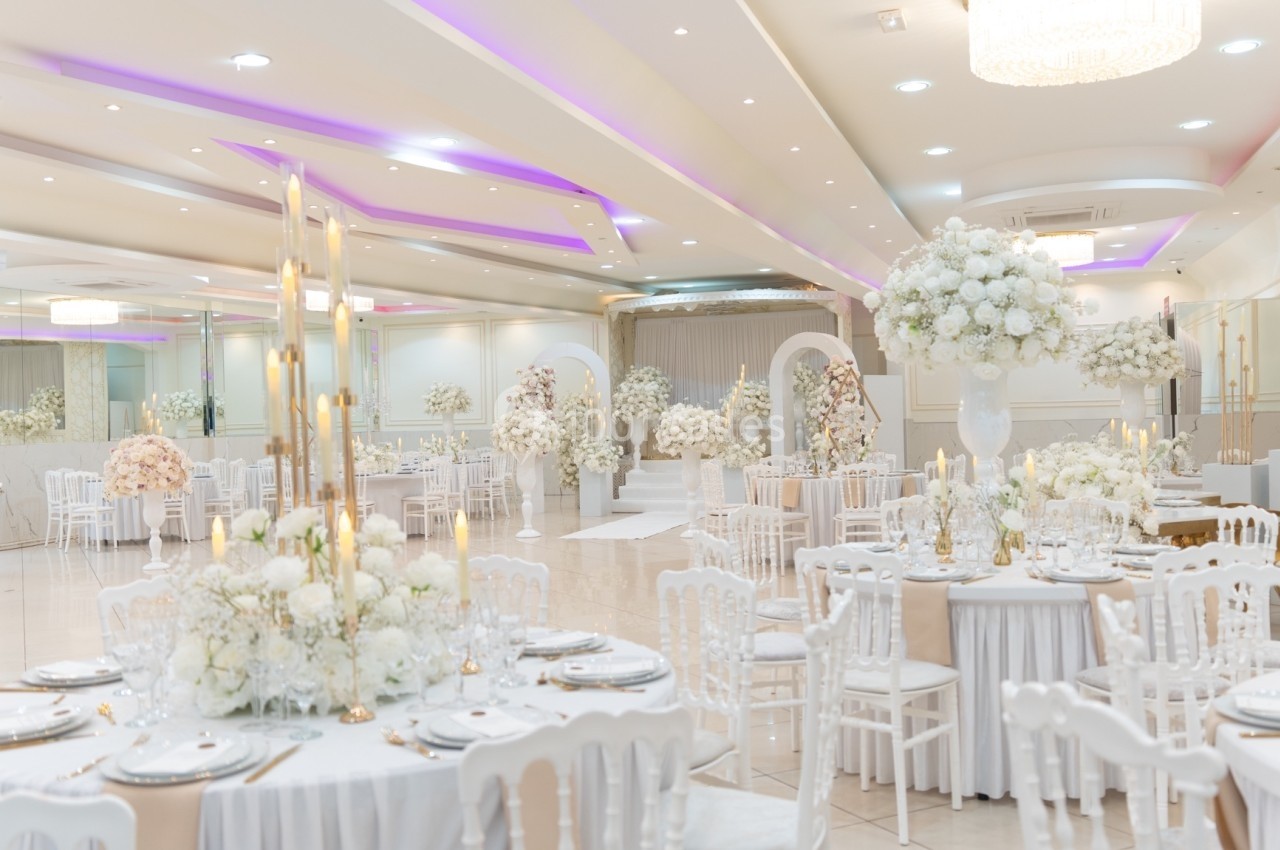 Salle de réception élégante décorée de fleurs blanches, tables dressées et éclairage tamisé.