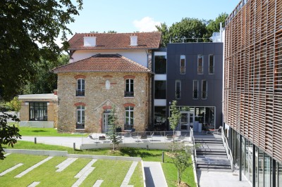Miniature Location salle Meudon (Hauts-de-Seine) - L'Ermitage #2 Chambre lumineuse avec un grand lit, des rideaux gris, une table basse et une vue sur un balcon avec végétation.