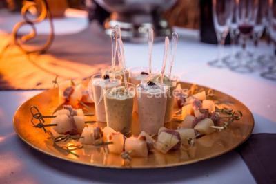 Plateau doré avec verrines et brochettes apéritives, disposé sur une table décorée pour un événement.