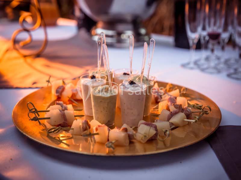 Plateau doré avec verrines et brochettes apéritives, disposé sur une table décorée pour un événement.