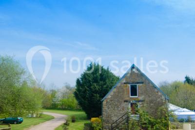 Intérieur d'un chalet en bois avec table, chaises recouvertes de fourrure, poêle allumé et vase de fleurs sur une table…