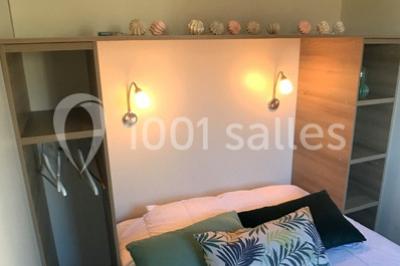 Intérieur d'un chalet en bois avec table, chaises recouvertes de fourrure, poêle allumé et vase de fleurs sur une table…