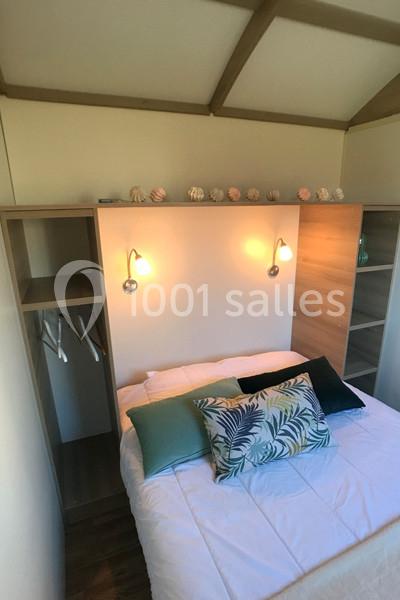 Lit double avec coussins décoratifs, encadré par des étagères en bois et éclairé par deux appliques murales.