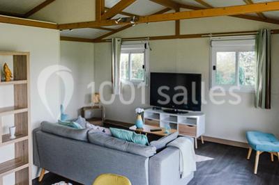 Intérieur d'un chalet en bois avec table, chaises recouvertes de fourrure, poêle allumé et vase de fleurs sur une table…