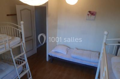 Intérieur d'un chalet en bois avec table, chaises recouvertes de fourrure, poêle allumé et vase de fleurs sur une table…